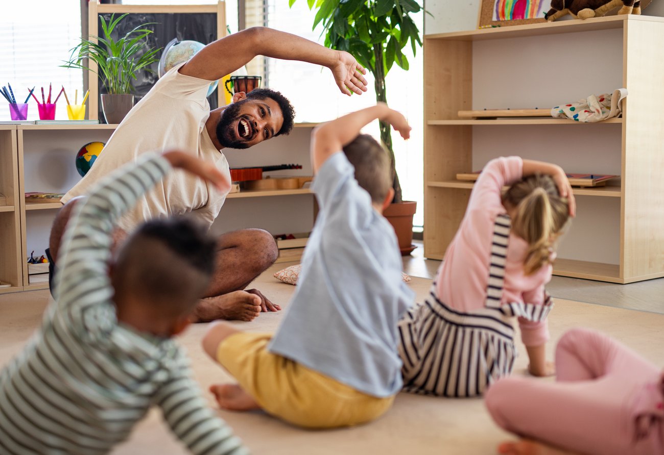 Erzieher macht Sportübungen mit Kindern 