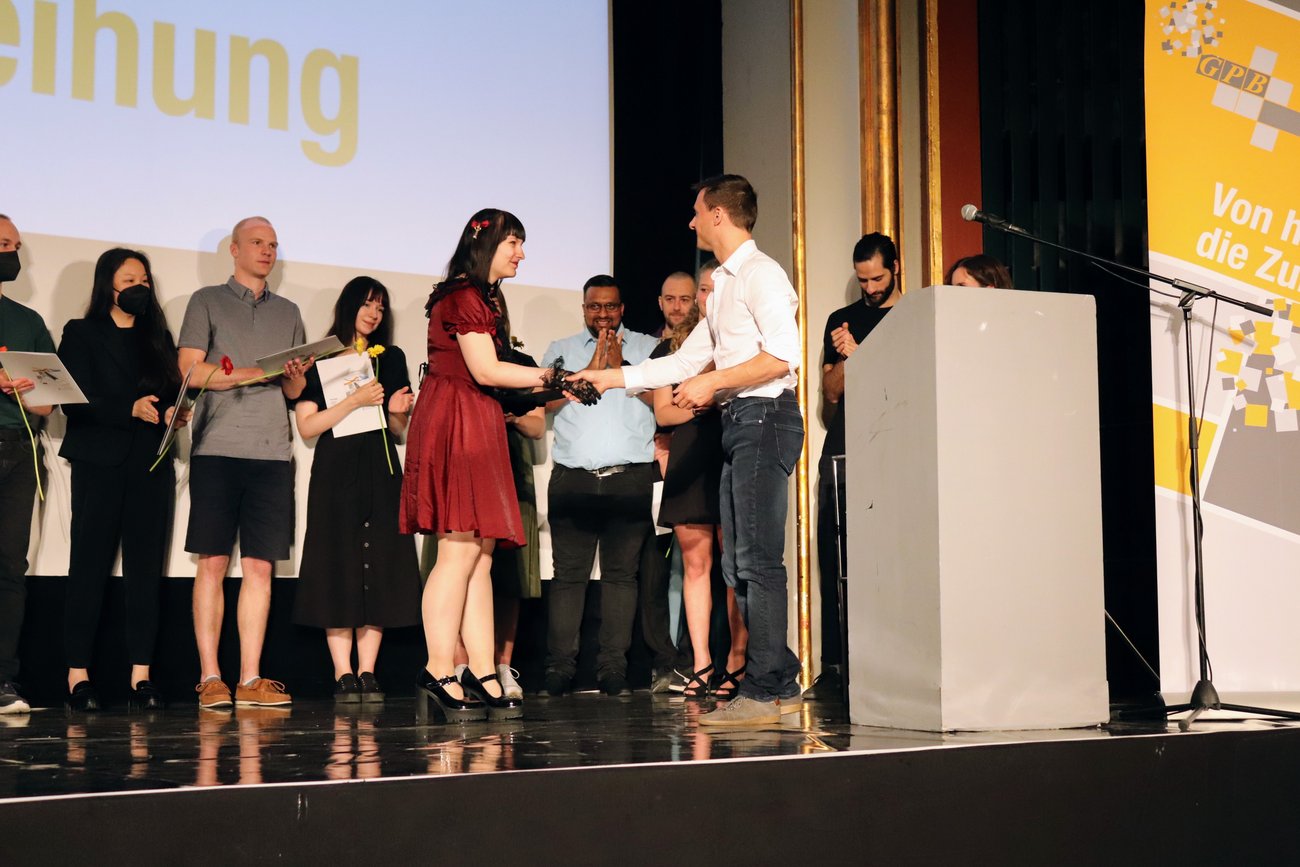 Schülerin in rotem kleid bekommt ihr Zeugnis auf der Bühne