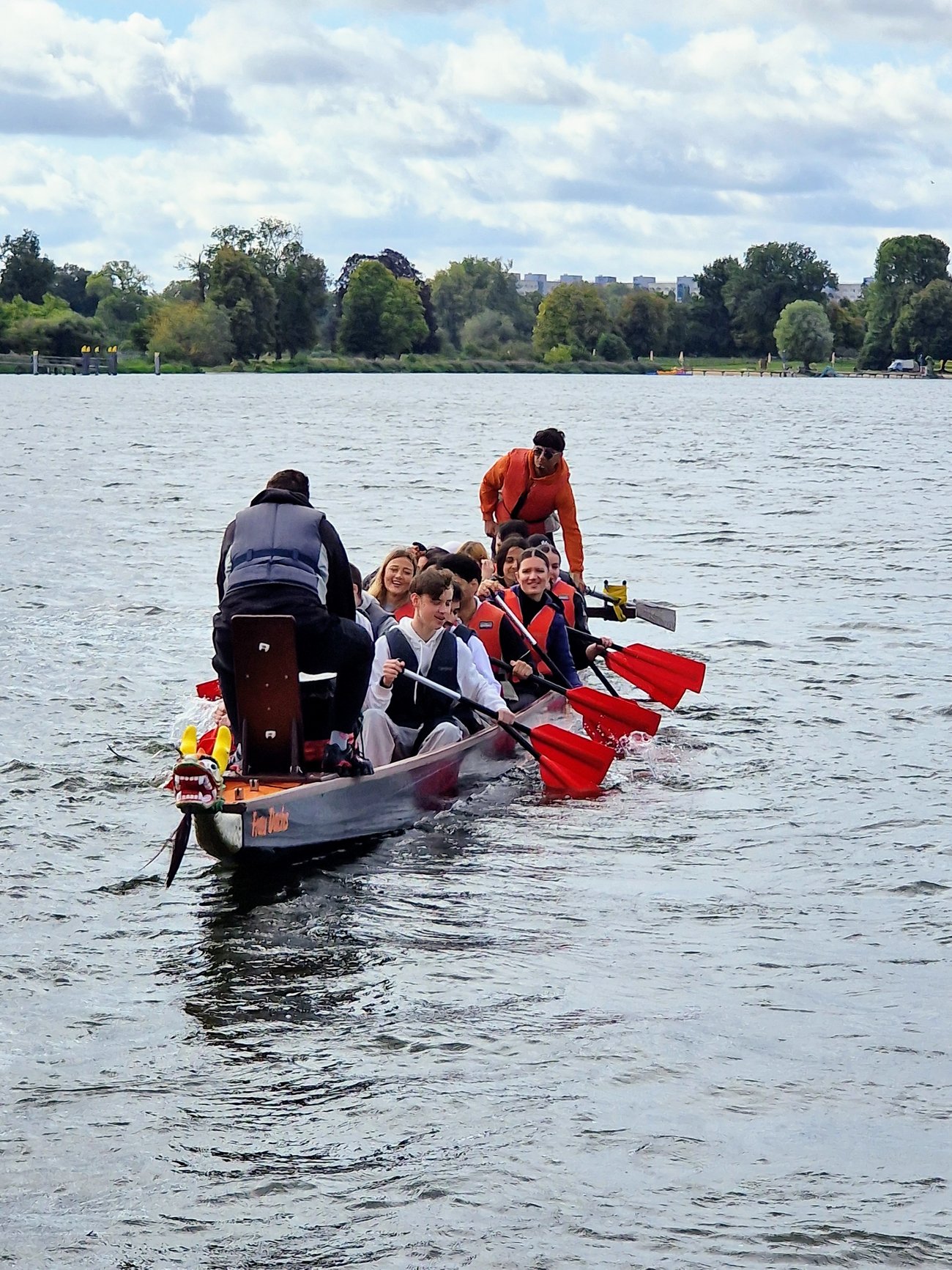 Schüler sitzen in einem Drachenboot, das auf einem breiten Fluss fährt