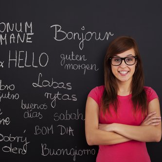eine junge Frau steht vor einer Tafel mit Wörtern in verschiedenen Sprachen