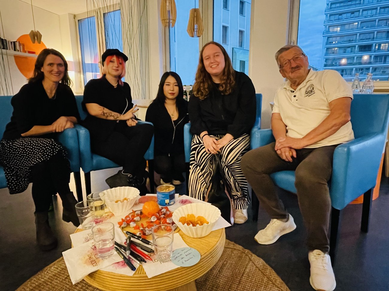 5 Personen sitzen um einen kleinen Tisch