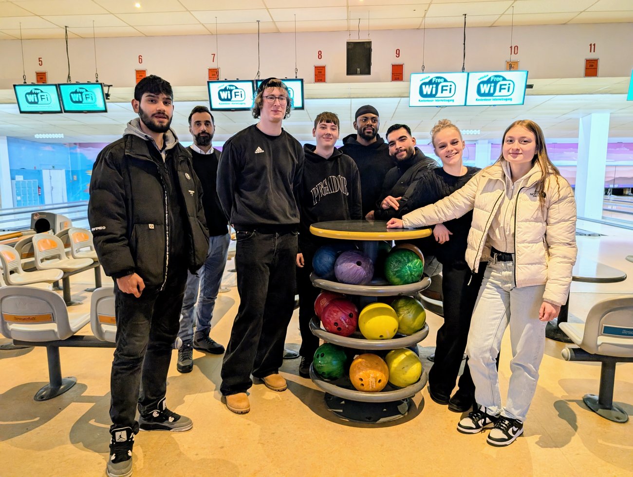 Schülerinnen und Schüler an einem runden Tisch mit Bowlingkugeln