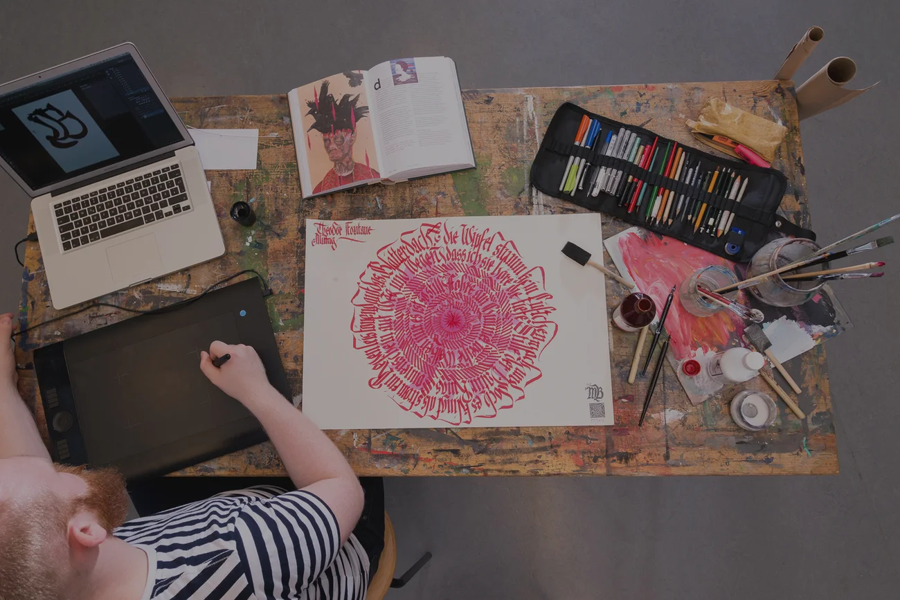 Grafikdesigner bei der Arbeit an Kalligrafie und digitaler Illustration am Schreibtisch