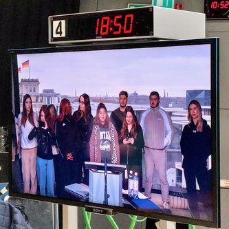 Gruppe von Schülern vor einem großen Bildschirm