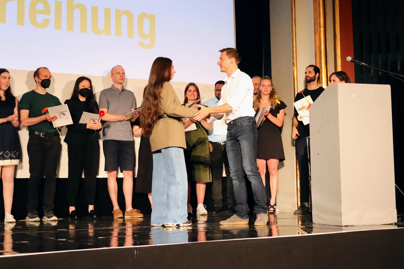 Schülerin bekommt ihr Zeugnis von einem Lehrer überreicht