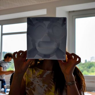 Gesicht von Schülerin hinter gemaltem Gesicht