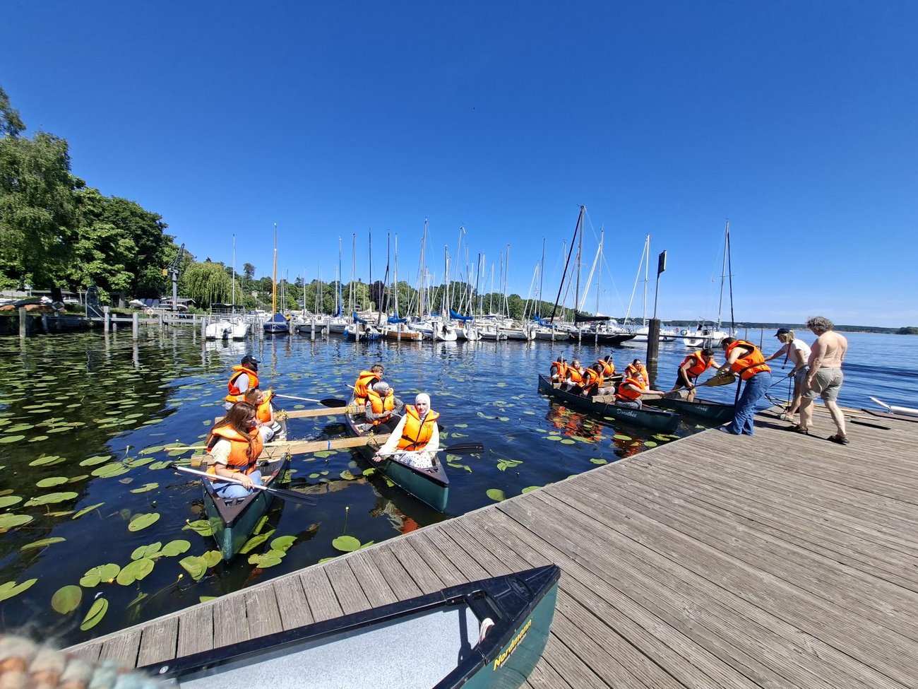 junge Menschen in Schwimmwesten sitzen in Kanus