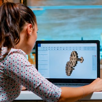 Frau sitzt vor einem Bildschirm mit einem 3D-Motiv