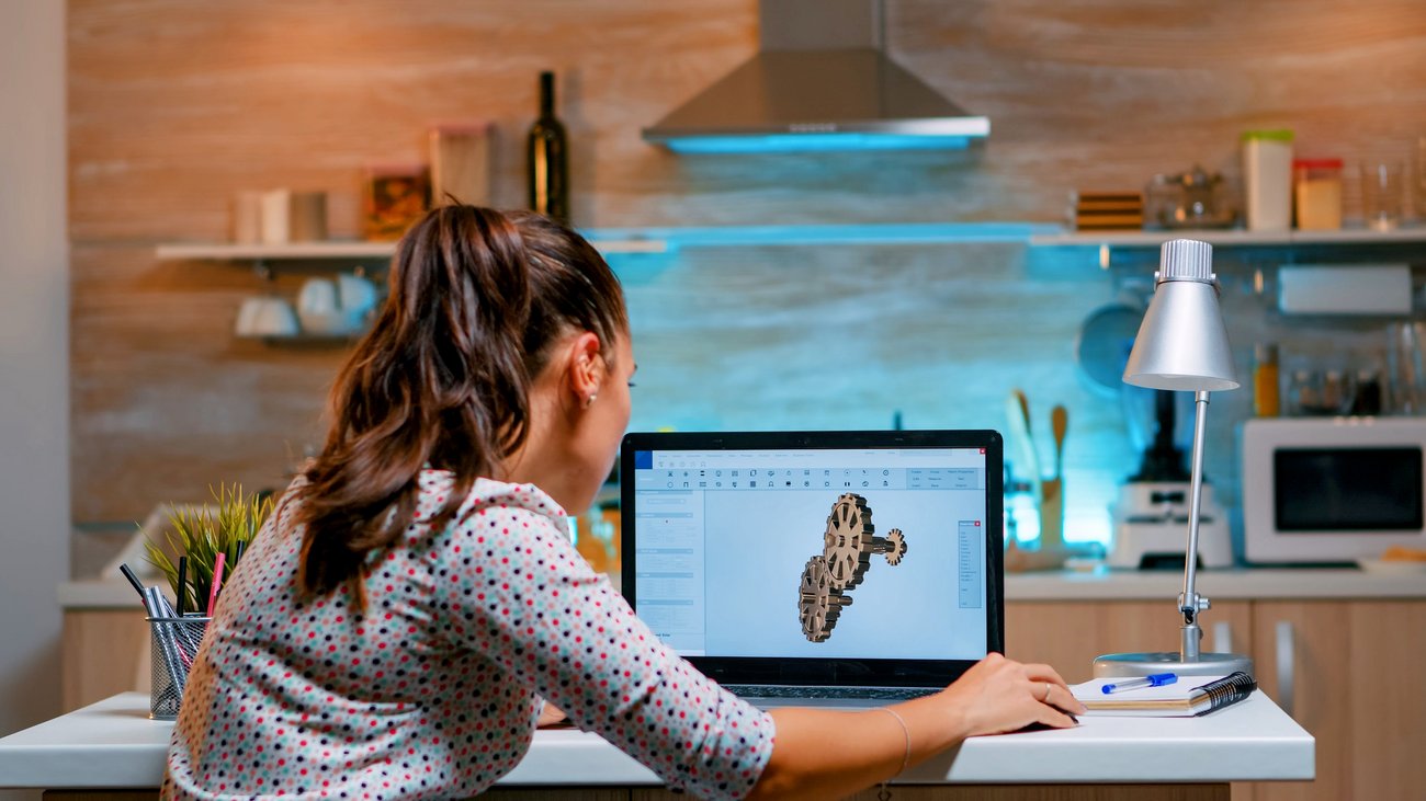 Frau sitzt vor einem Bildschirm mit einem 3D-Motiv
