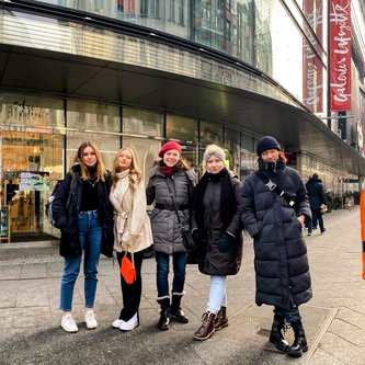eine Lehrerin mit vier Schülerinnen vor der Galerie Lafayette