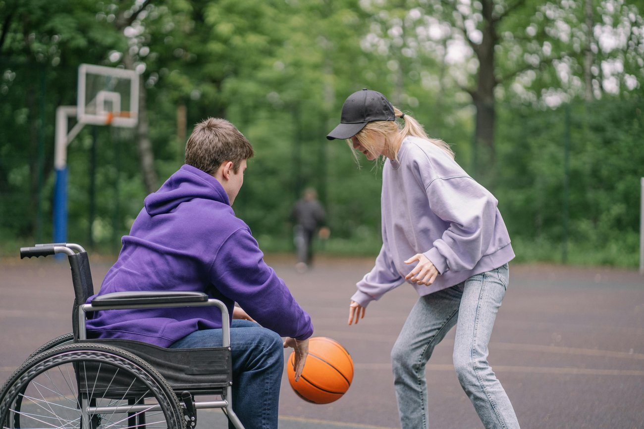 Frau spielt Ball mit Mann im Rollstuhl