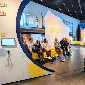 Menschen sitzen in einem Raum und hören zu