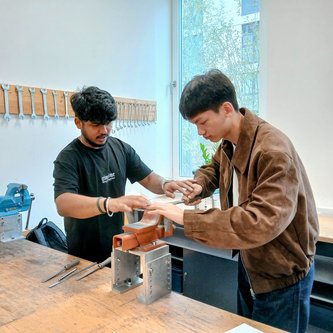 koreanischer Schüler an der Werkbank mit deutschem Schüler als Helfer