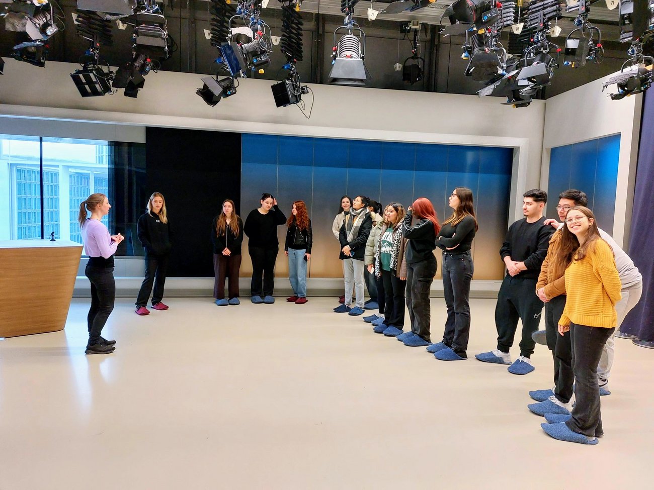 Gruppe von Schülerinnen und Schülern in einem Fernsehstudio mit vielen Scheinwerfern an der Decke