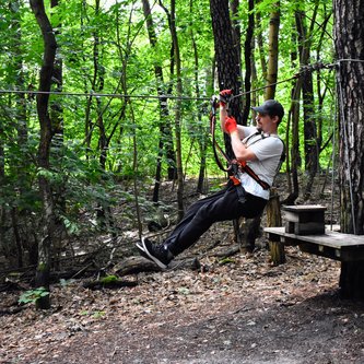 ein Schüler an der Seilrutsche im Kletterwald