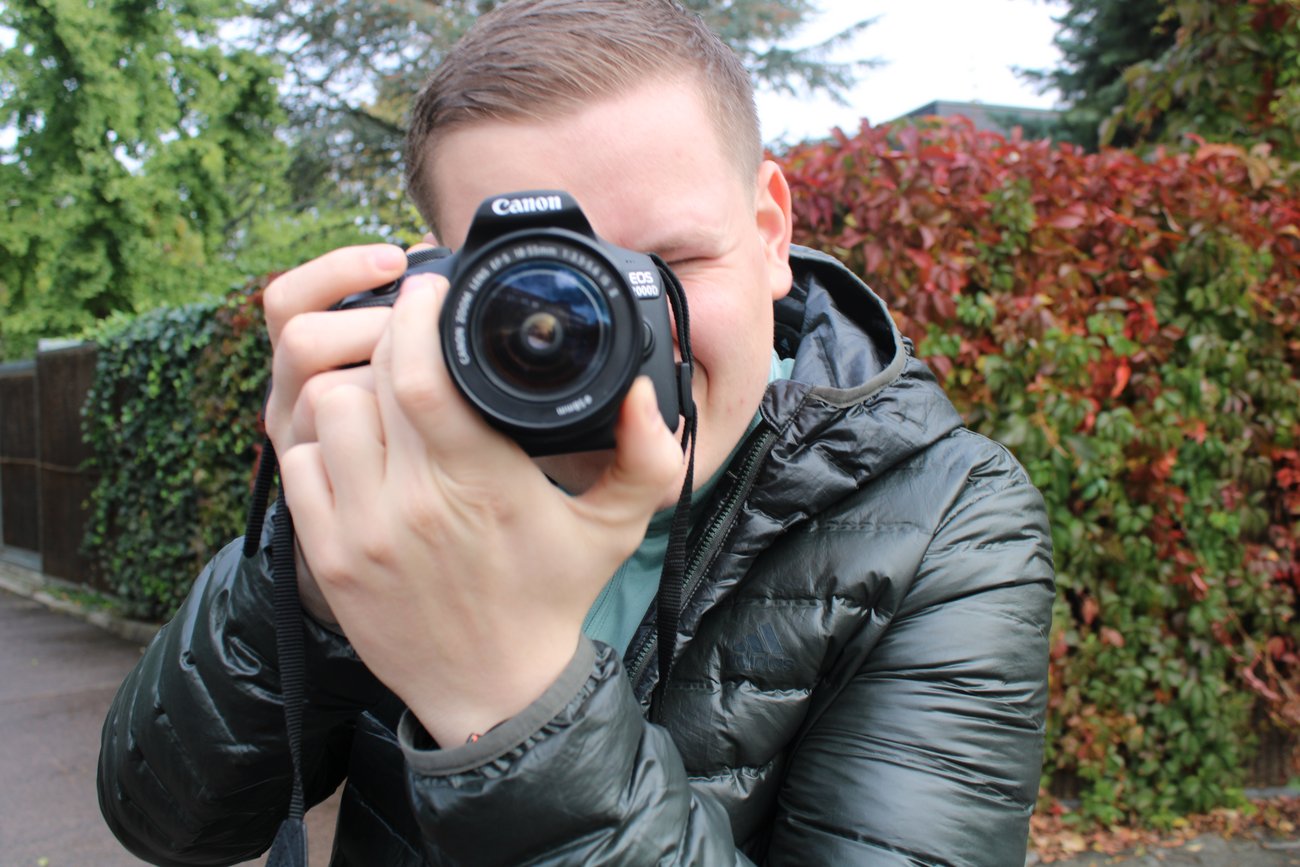 Mann mit Kamera vor dem Gesicht