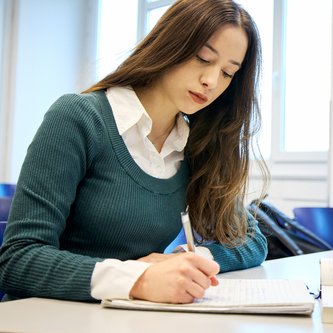 Schülerin schreibt am Tisch