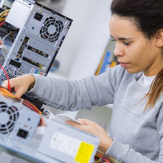 junge Frau mit aufgeschraubtem PC steckt ein Kabel an