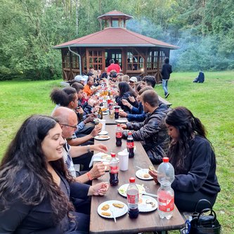 viele Schüler sitzen an einem langen Tisch und essen