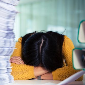 Überforderte Schülerin mit Kopf auf Schulbank