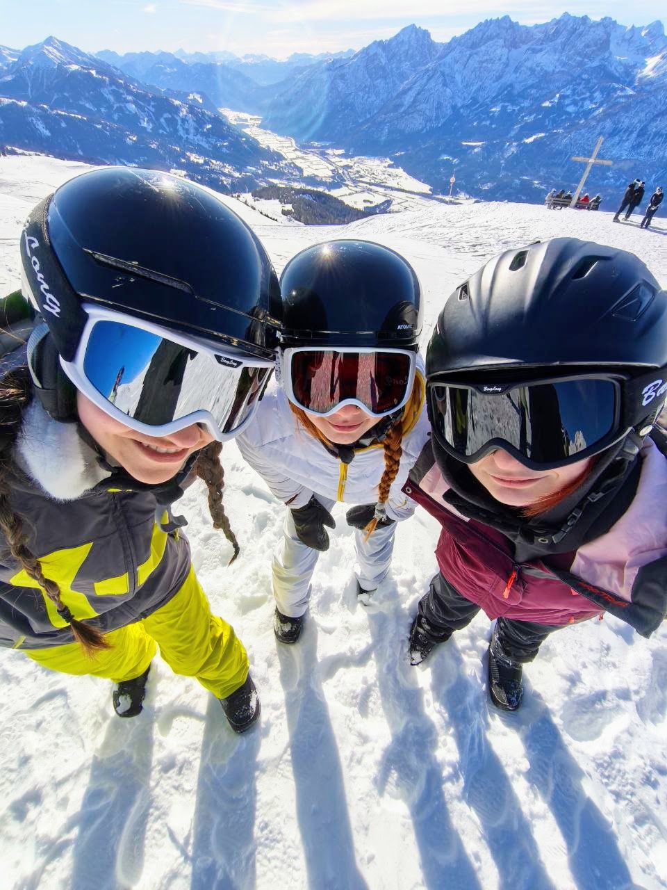 Drei Skifahrer mit Skibrillen stehen auf dem Berg