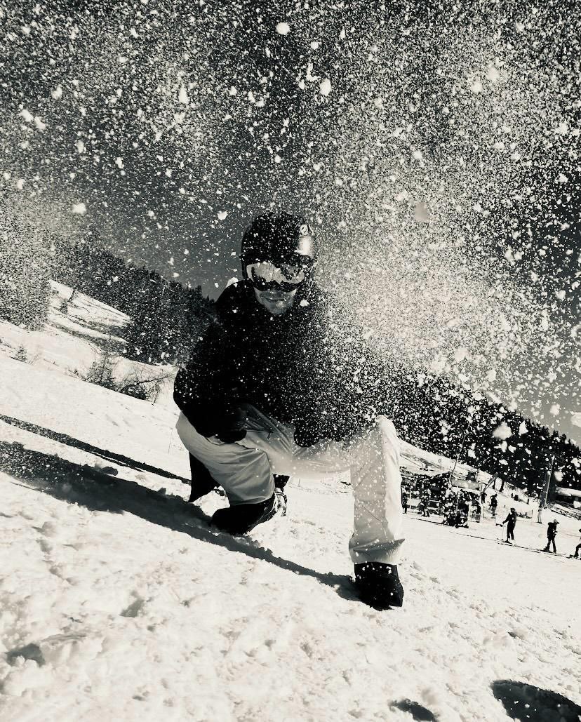 Mensch mit Skihelm und aufgewirbeltem Schnee in schwarz weiß
